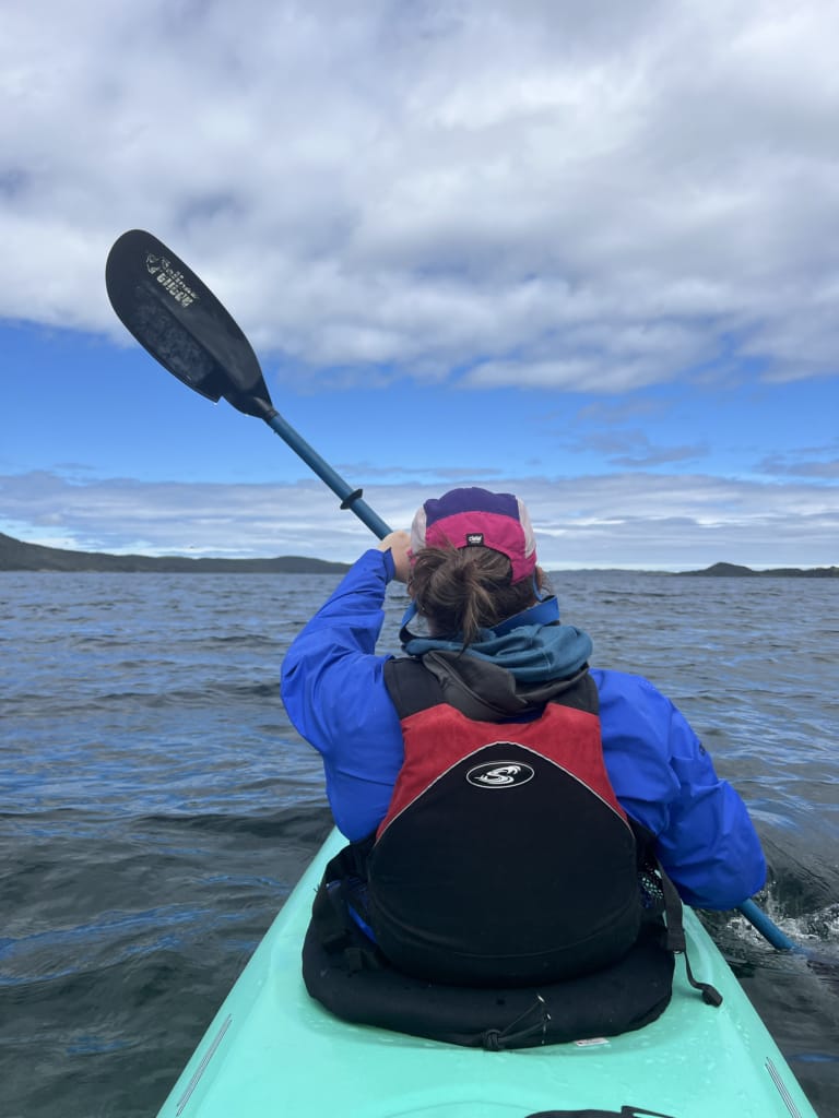 A woman kayaking in Terra Nova National Park shot from the rear seat of a double kayak