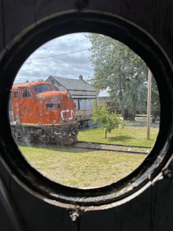 Looking through a round window to a train engine at the Central BC Railway Museum